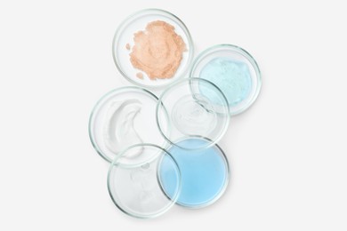 Many Petri dishes and cosmetic products on white background, top view