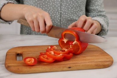 Photo of Cooking process. Woman cutting bell pepper at white countertop, closeup