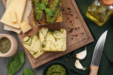 Freshly baked pesto bread with ingredients on grey table, flat lay
