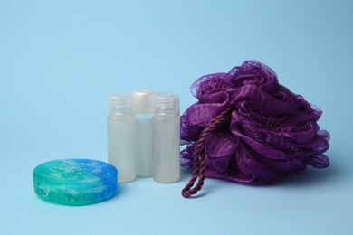 Purple shower puff and cosmetic products on light blue background