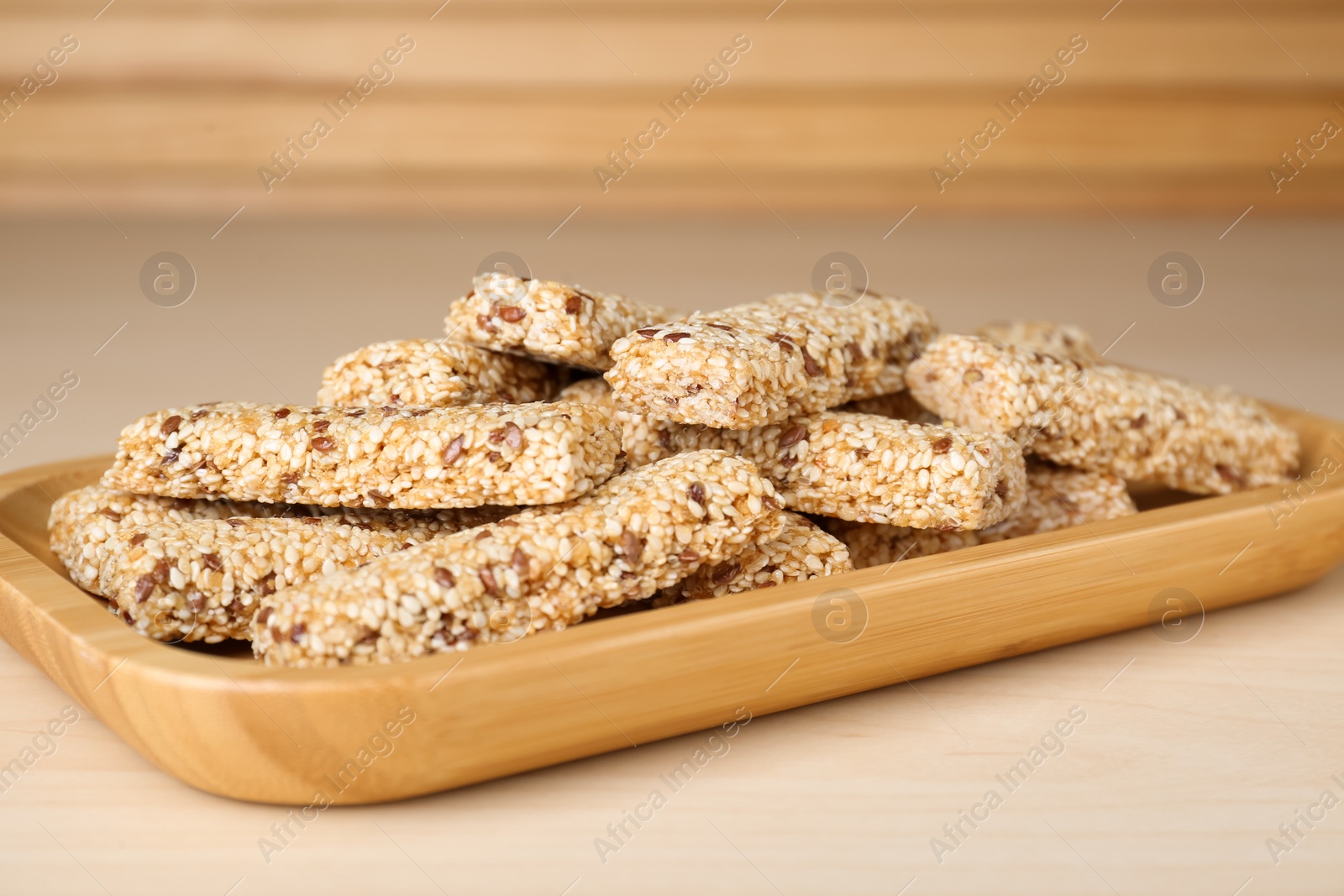 Photo of Plate with tasty sesame seed bars on wooden table, closeup