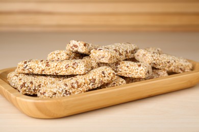 Photo of Plate with tasty sesame seed bars on wooden table, closeup