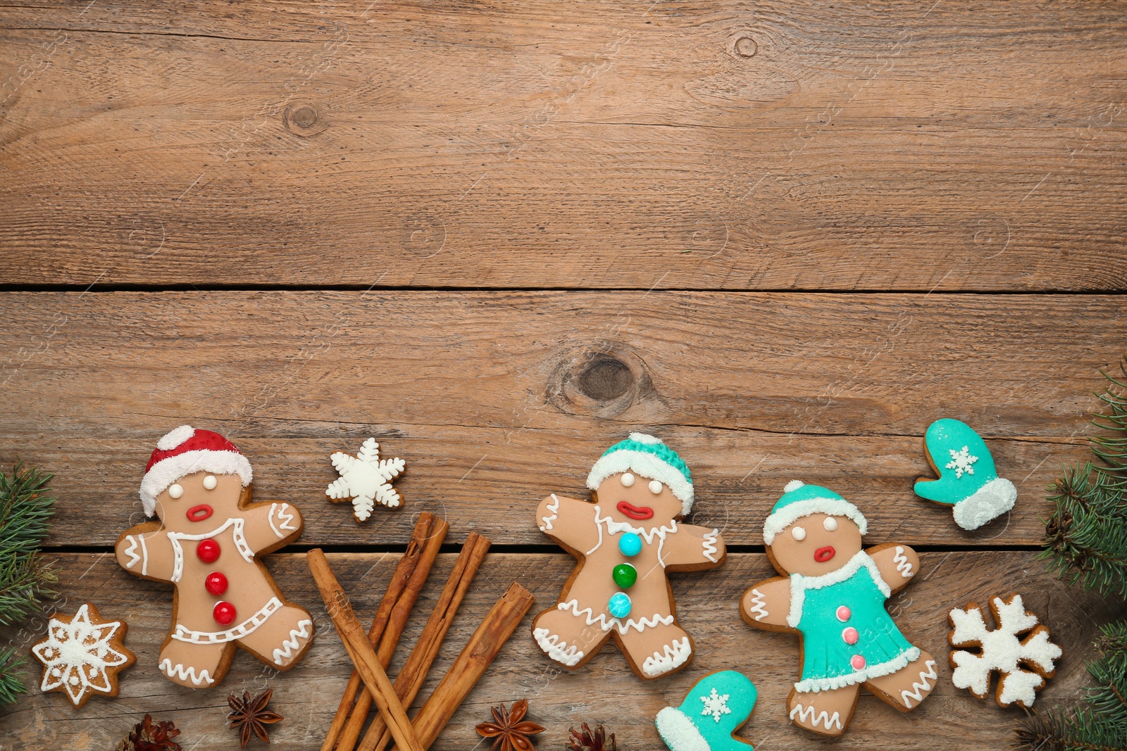 Photo of Delicious Christmas cookies, cinnamon and fir branches on wooden table, flat lay. Space for text