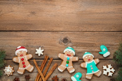 Photo of Delicious Christmas cookies, cinnamon and fir branches on wooden table, flat lay. Space for text