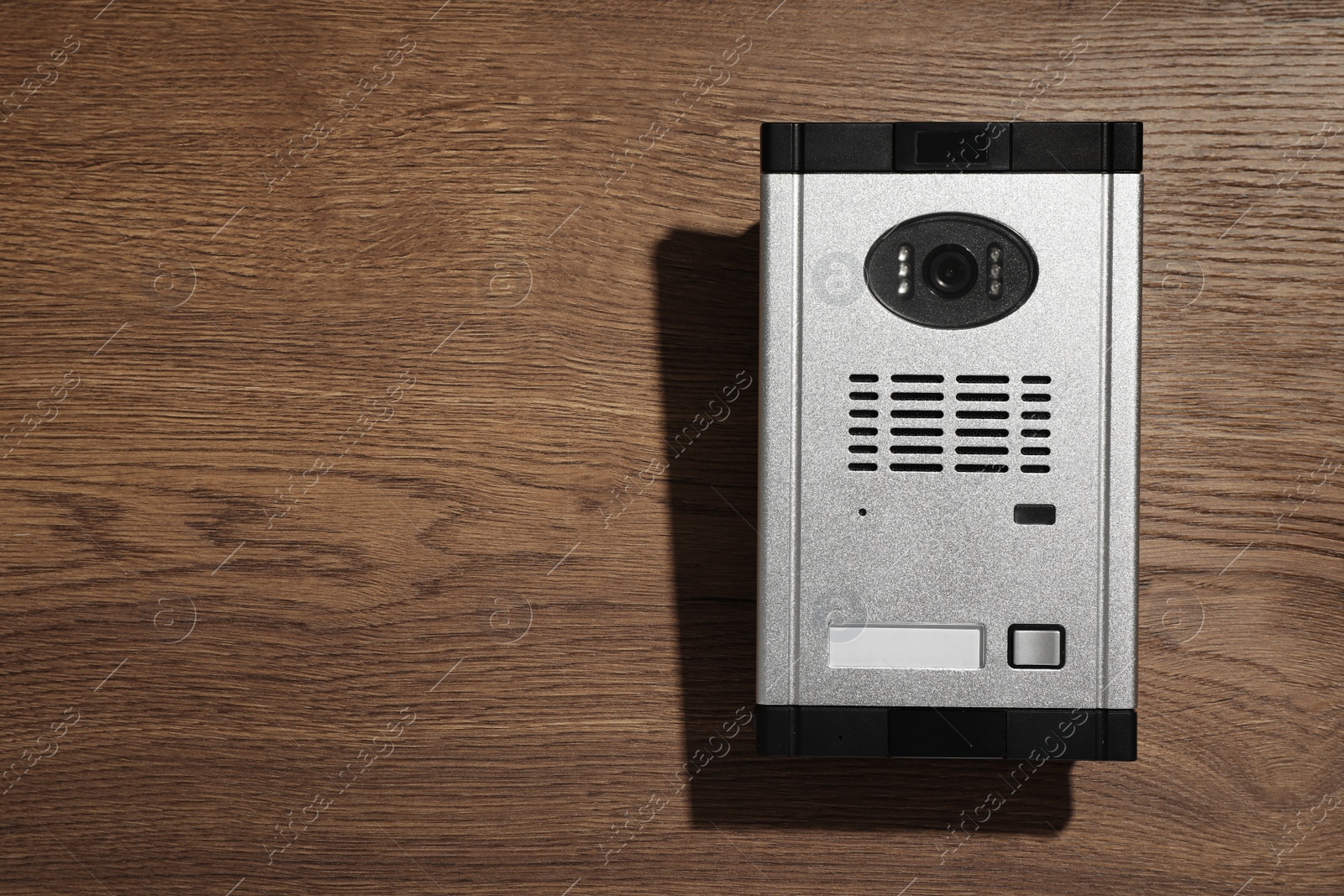 Photo of Modern intercom system with camera on wooden background, top view. Space for text