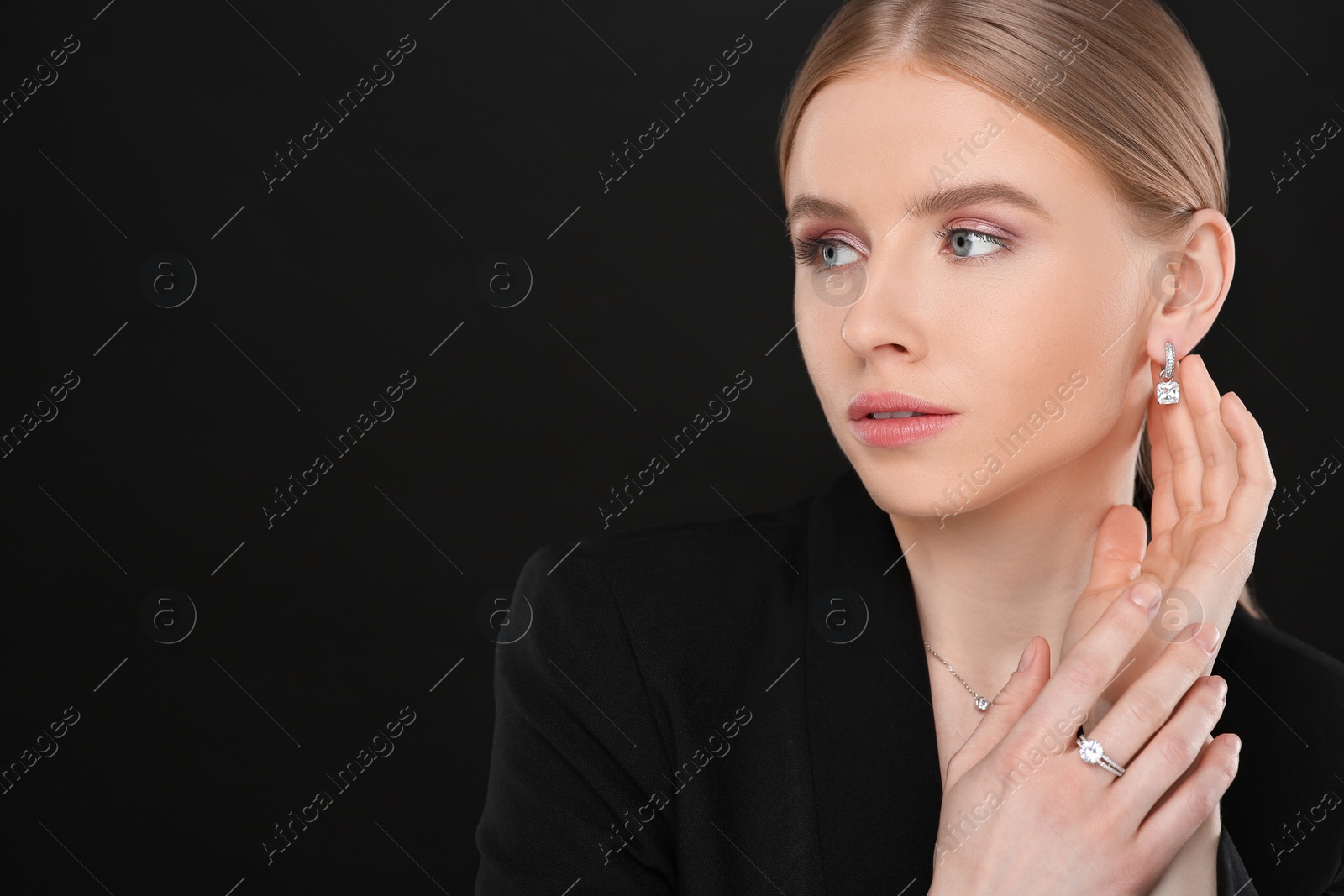 Photo of Beautiful young woman with elegant jewelry on black background, space for text