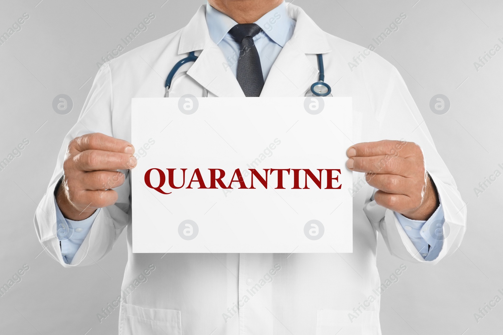 Image of Doctor holding sign with text QUARANTINE on light grey background, closeup. Stay at home during coronavirus outbreak