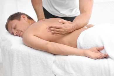 Relaxed man receiving back massage in wellness center