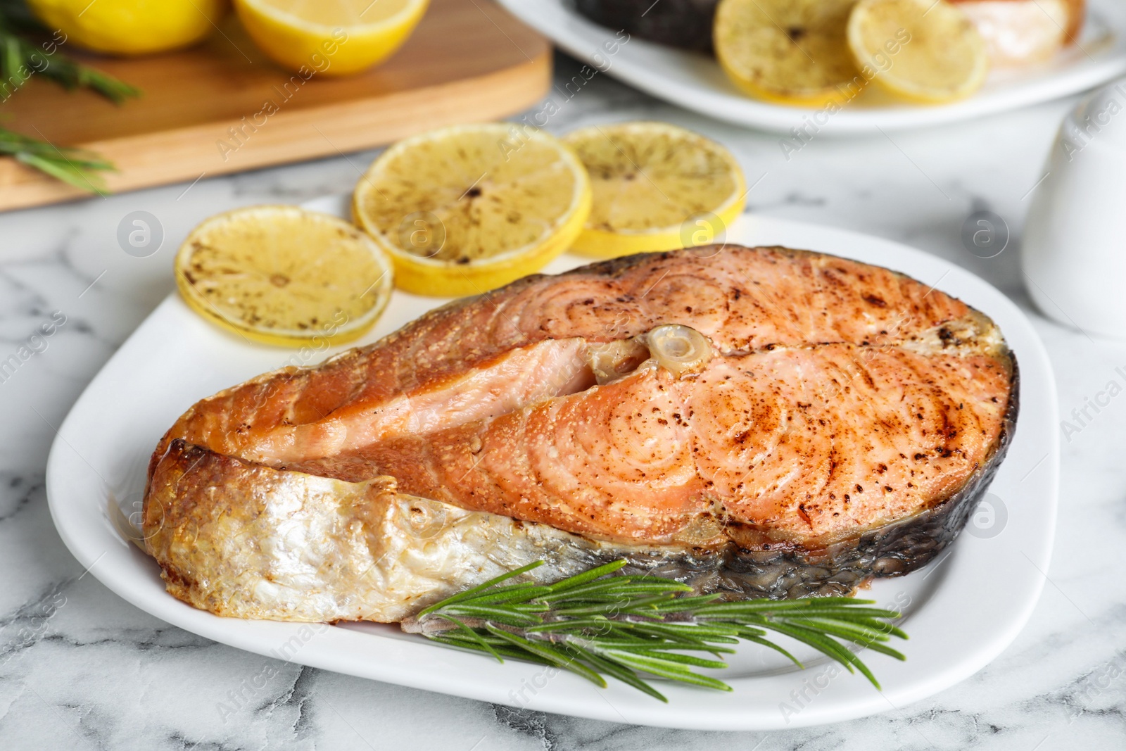 Photo of Tasty cooked red fish on white marble table, closeup