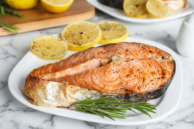 Photo of Tasty cooked red fish on white marble table, closeup