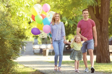 Happy family with colorful balloons in park on sunny day