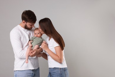 Photo of Happy family. Parents with their cute baby on grey background, space for text