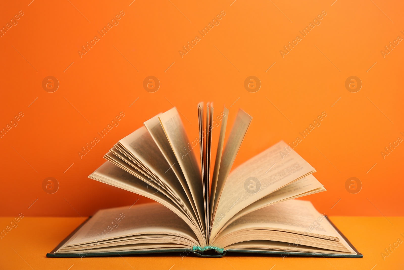 Photo of Open old hardcover book on orange background