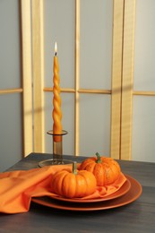 Photo of Burning candle and fresh pumpkins on wooden table indoors