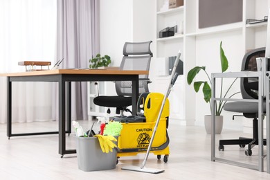 Cleaning service. Mop, bucket with supplies and wet floor sign in office