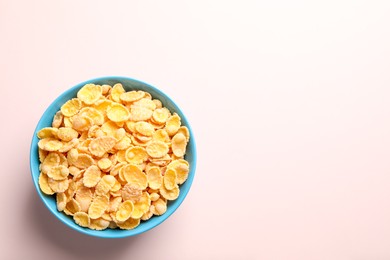 Photo of Bowl of tasty crispy corn flakes on light background, top view. Space for text