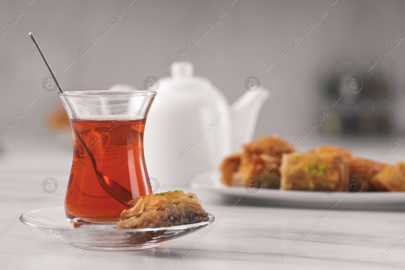Photo of Glass of traditional Turkish tea and delicious baklava on white table, space for text