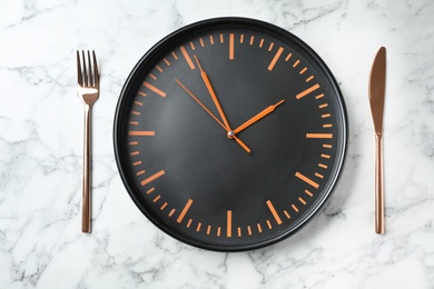 Flat lay composition with clock and utensils on marble background. Time management