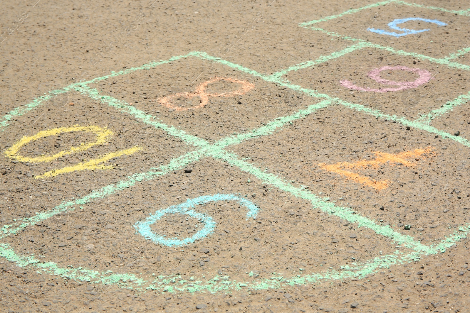 Photo of Hopscotch drawn with colorful chalk on asphalt outdoors, closeup