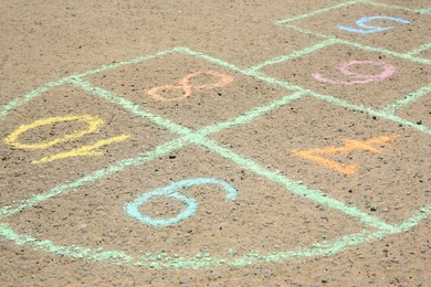 Hopscotch drawn with colorful chalk on asphalt outdoors, closeup