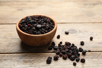 Photo of Bowl and dried black currant berries on wooden table