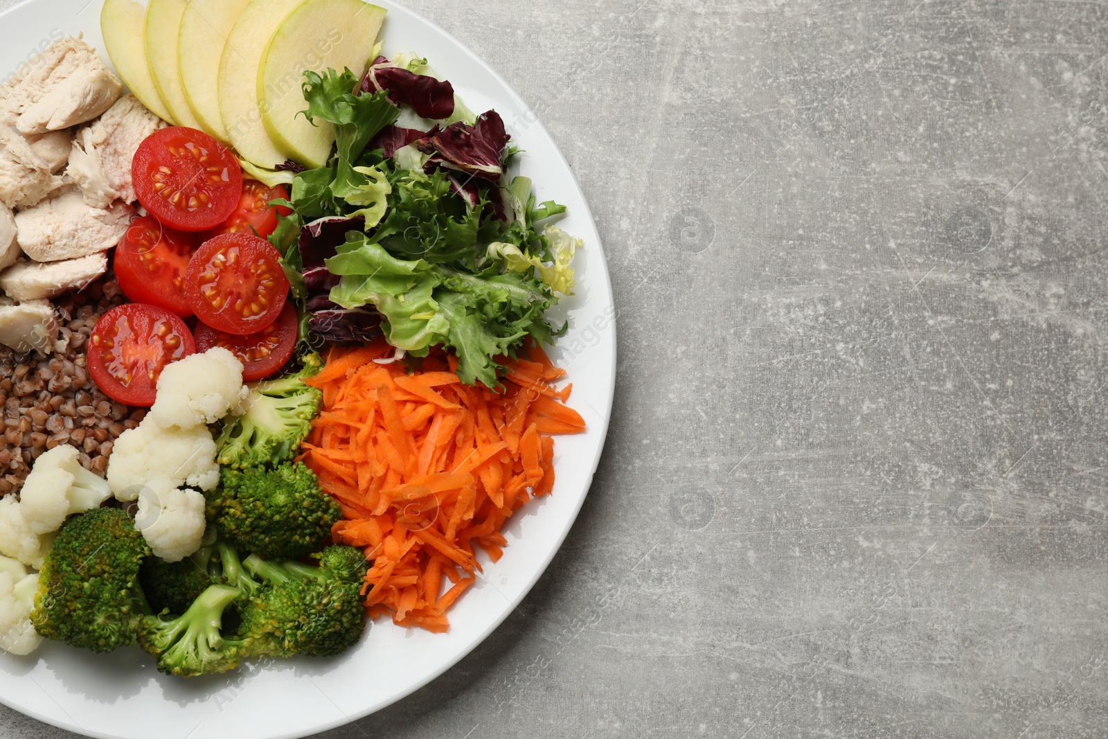 Photo of Balanced diet and healthy foods. Plate with different delicious products on grey table, top view. Space for text