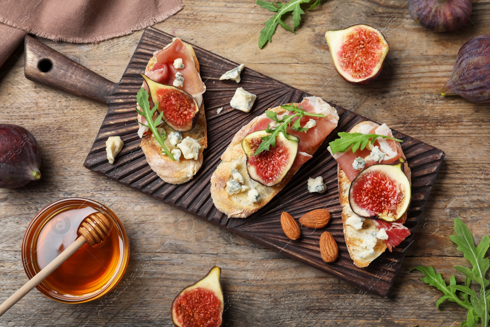 Photo of Sandwiches with ripe figs and prosciutto served on wooden table, flat lay