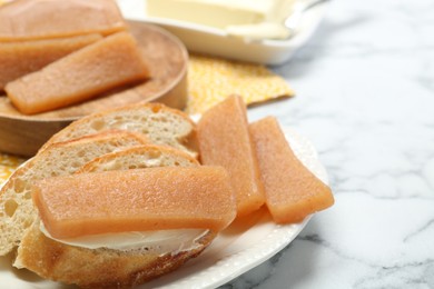 Photo of Delicious quince paste and bread on white marble table, closeup. Space for text