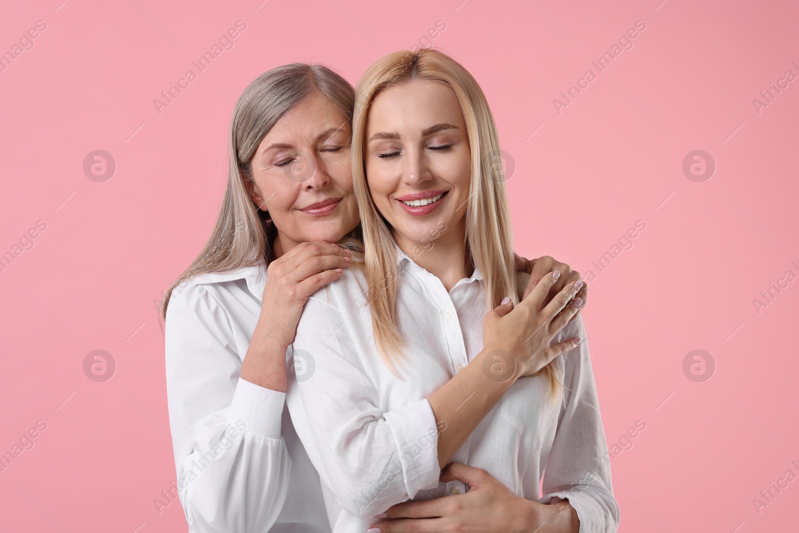 Photo of Family portrait of young woman and her mother on pink background