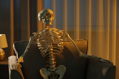 Photo of Waiting concept. Human skeleton sitting in armchair indoors