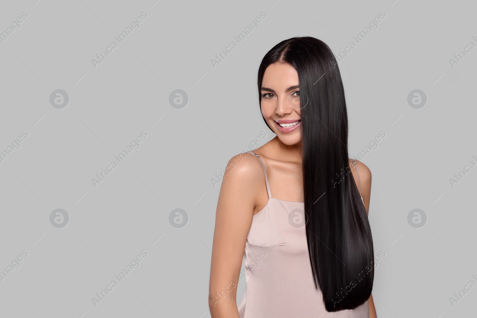 Photo of Portrait of beautiful young woman with healthy strong hair on light grey background, space for text