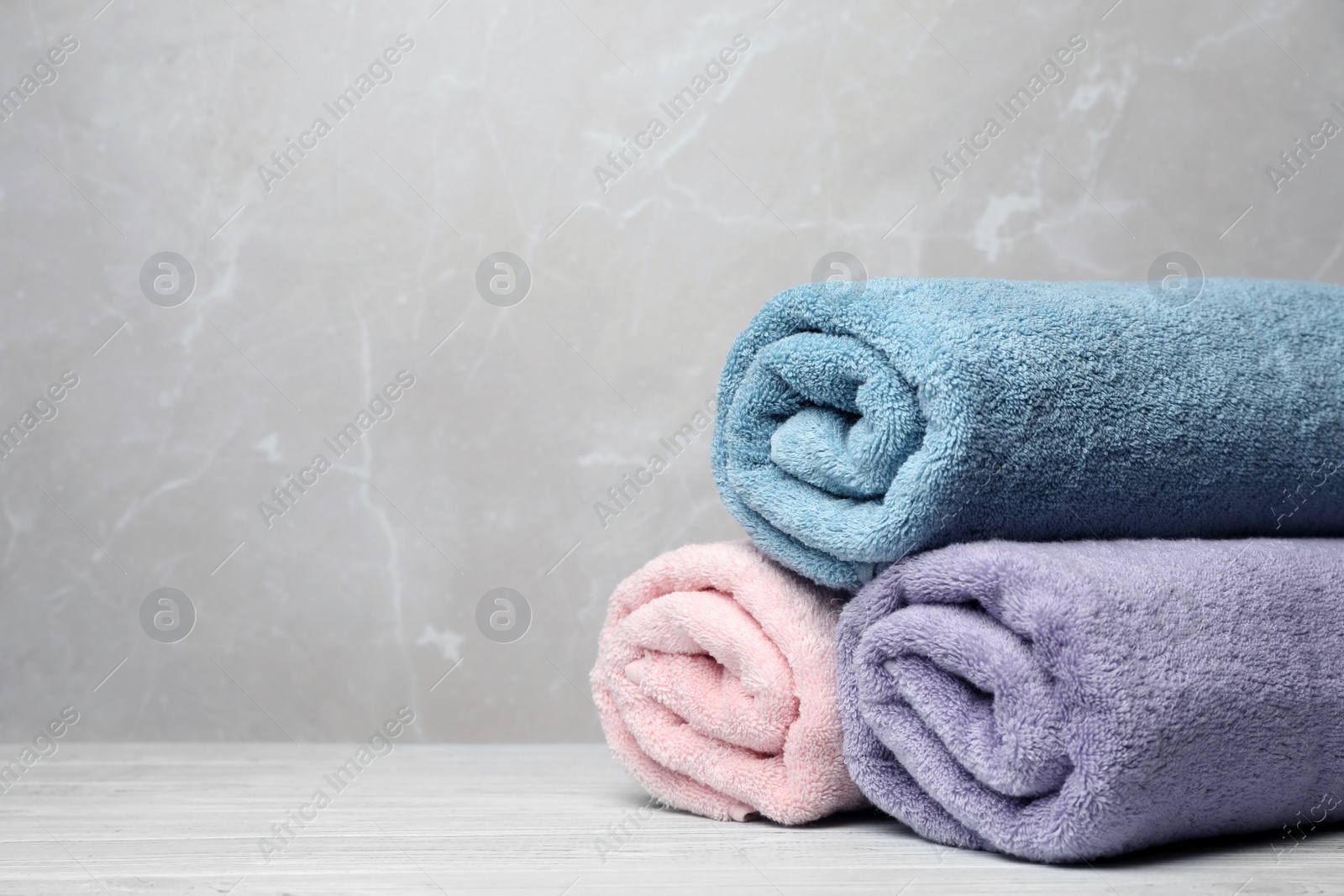 Photo of Pile of fresh rolled towels on table. Space for text