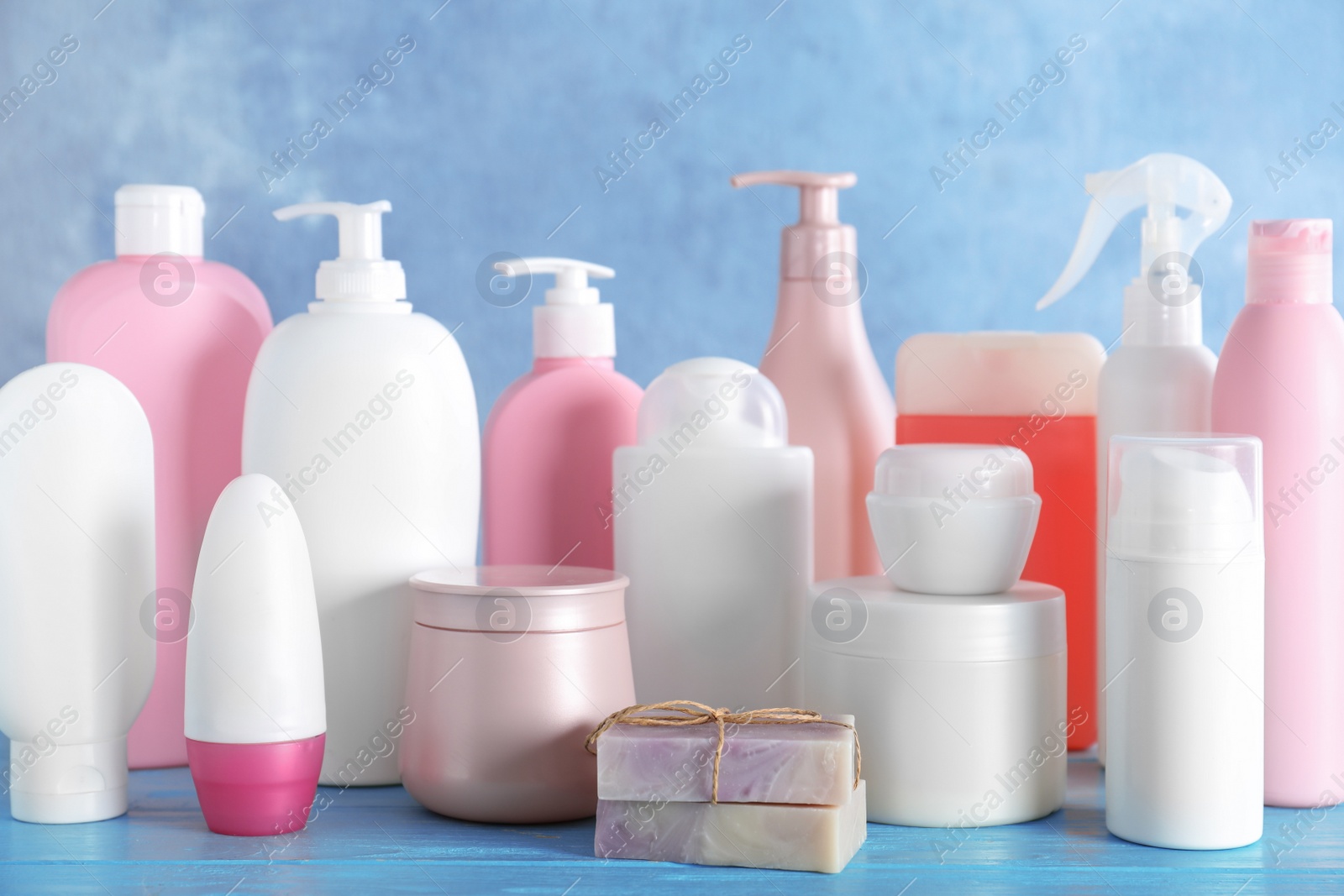 Photo of Different body care products on wooden table against blue background