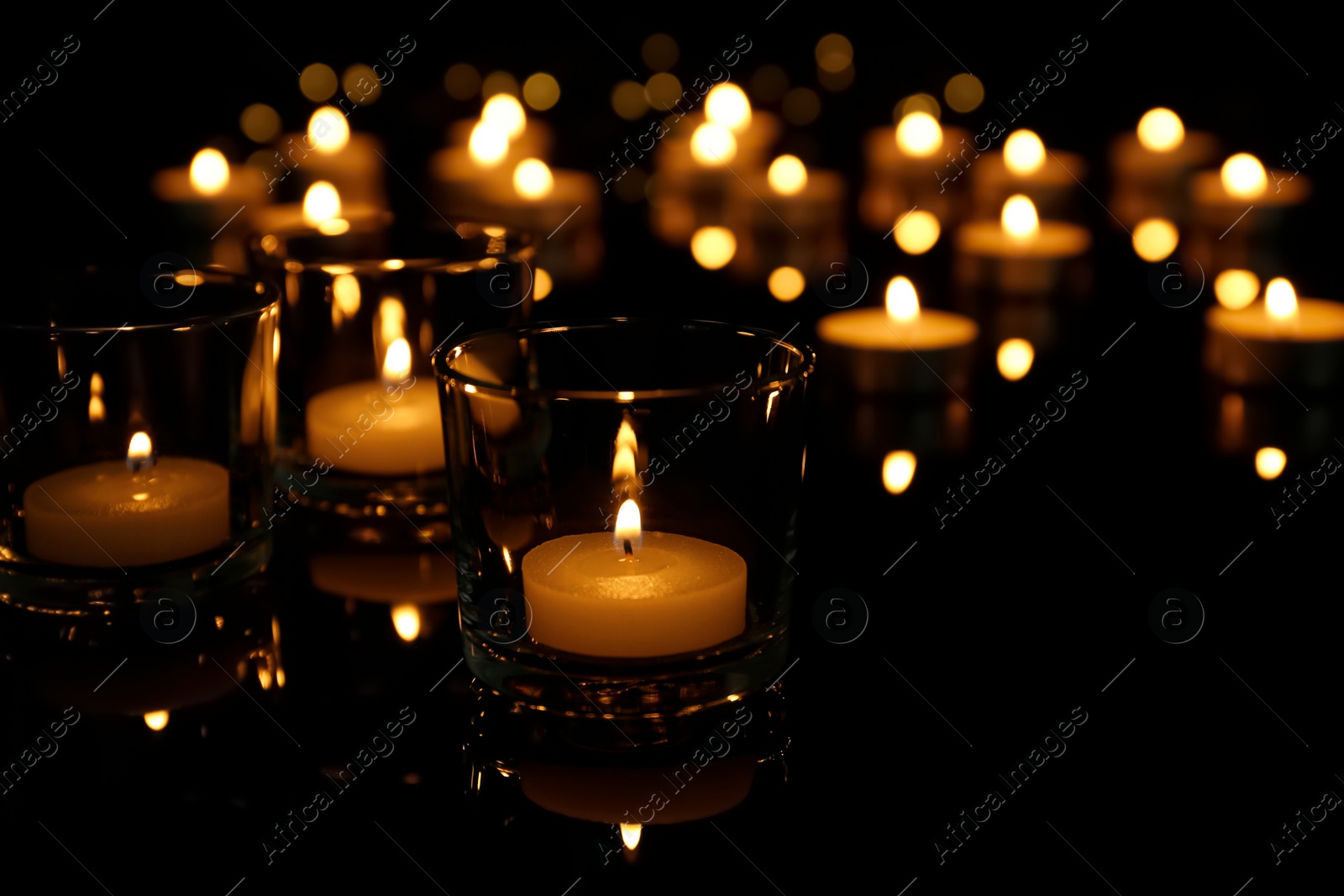 Photo of Burning candles in glass holders on table