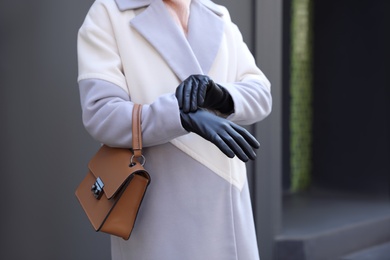 Photo of Woman with leather gloves and stylish bag outdoors, closeup