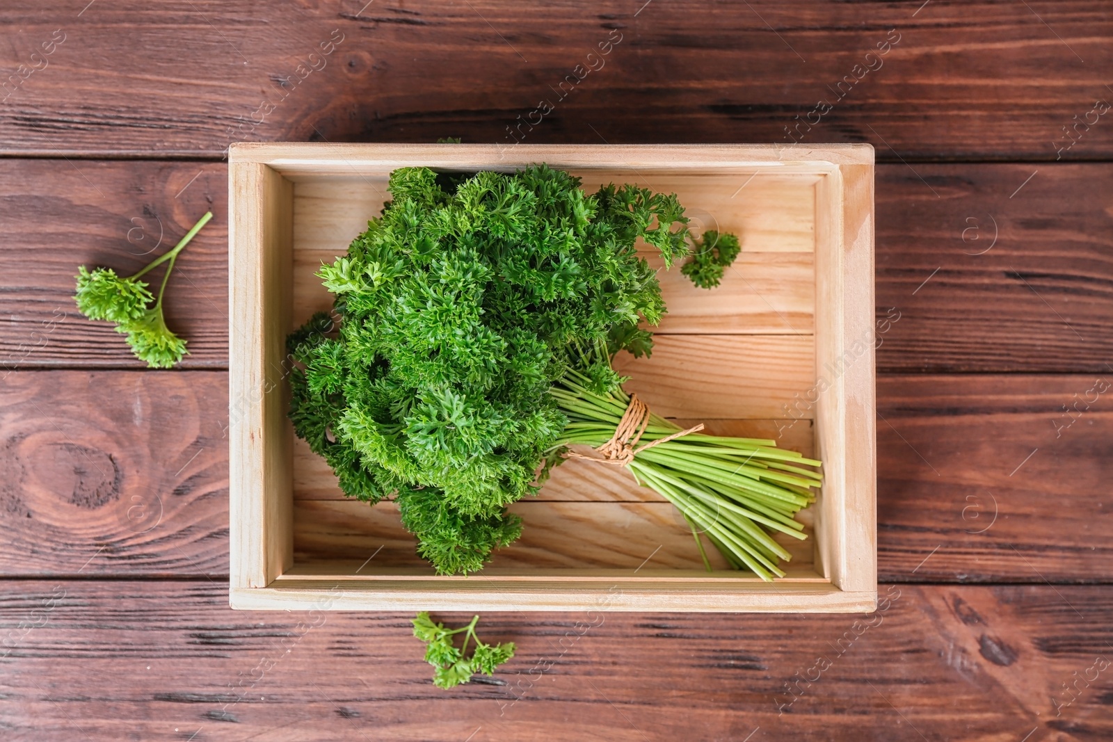 Photo of Crate with fresh green parsley on wooden background, top view