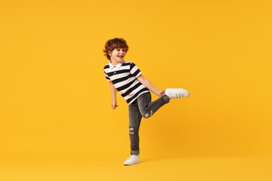 Photo of Happy little boy dancing on yellow background