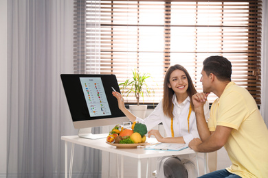 Photo of Young nutritionist consulting patient at table in clinic