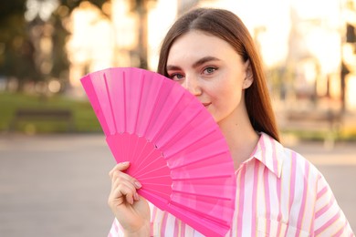 Photo of Beautiful young woman holding hand fan outdoors