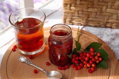 Tasty hot drink, jam and viburnum berries on wooden board indoors