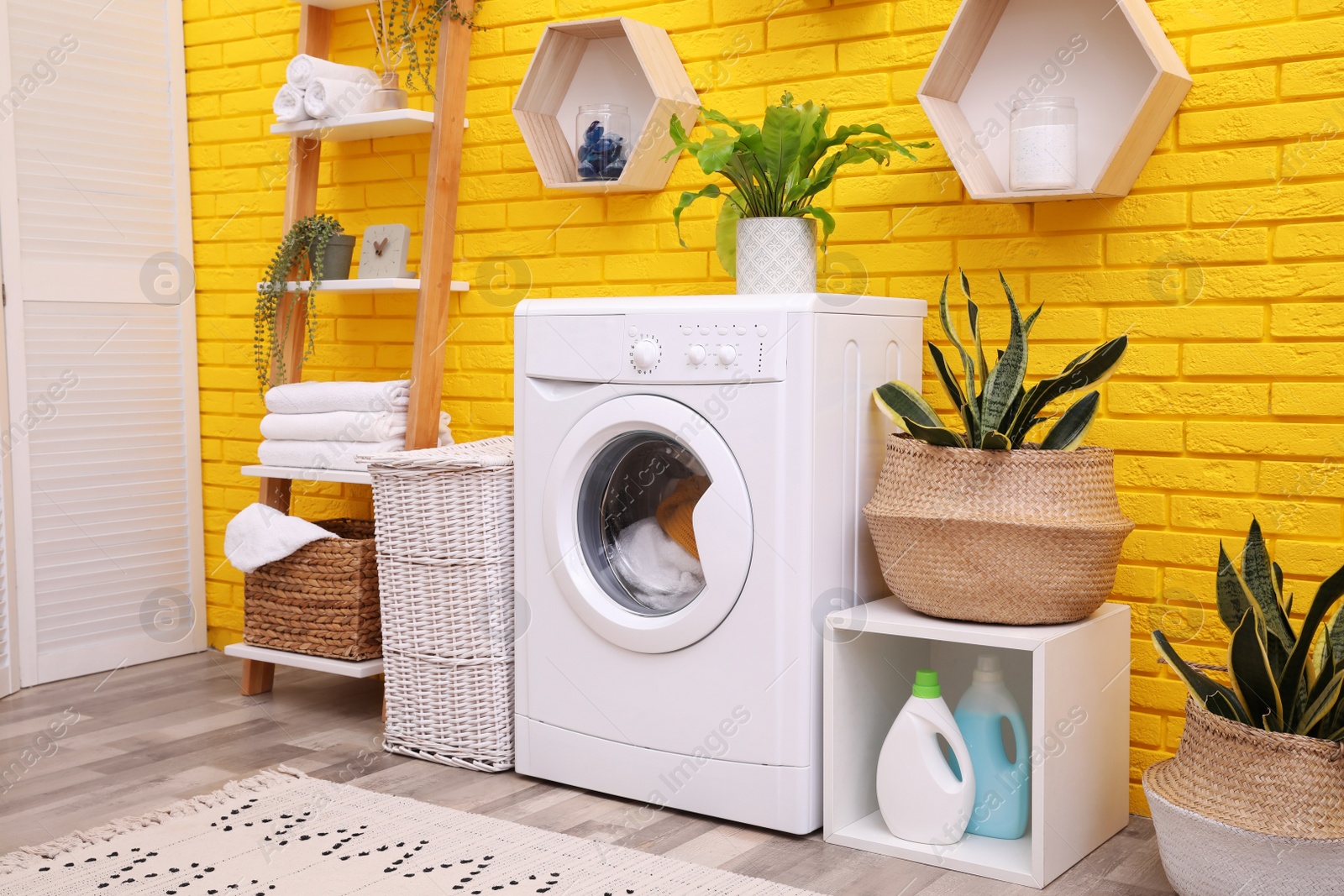 Photo of Laundry room interior with modern washing machine near yellow brick wall