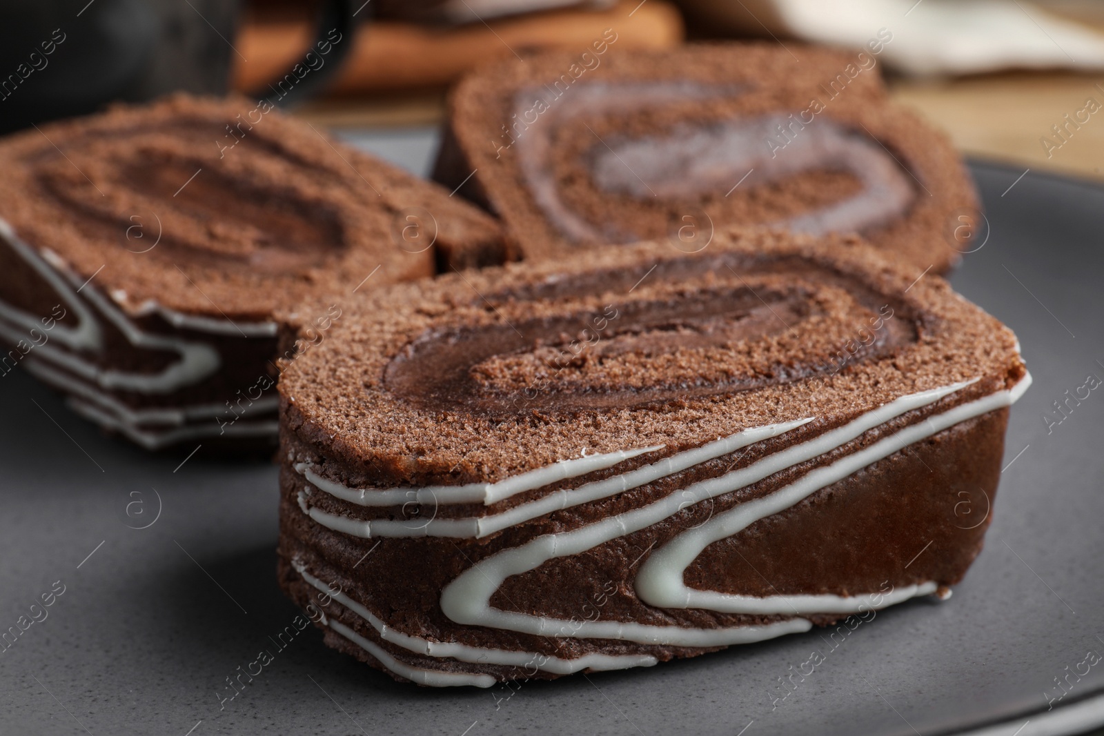 Photo of Tasty chocolate cake roll with cream on plate, closeup