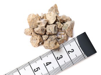 Photo of Pile of kidney stones and measuring tape on white background, top view