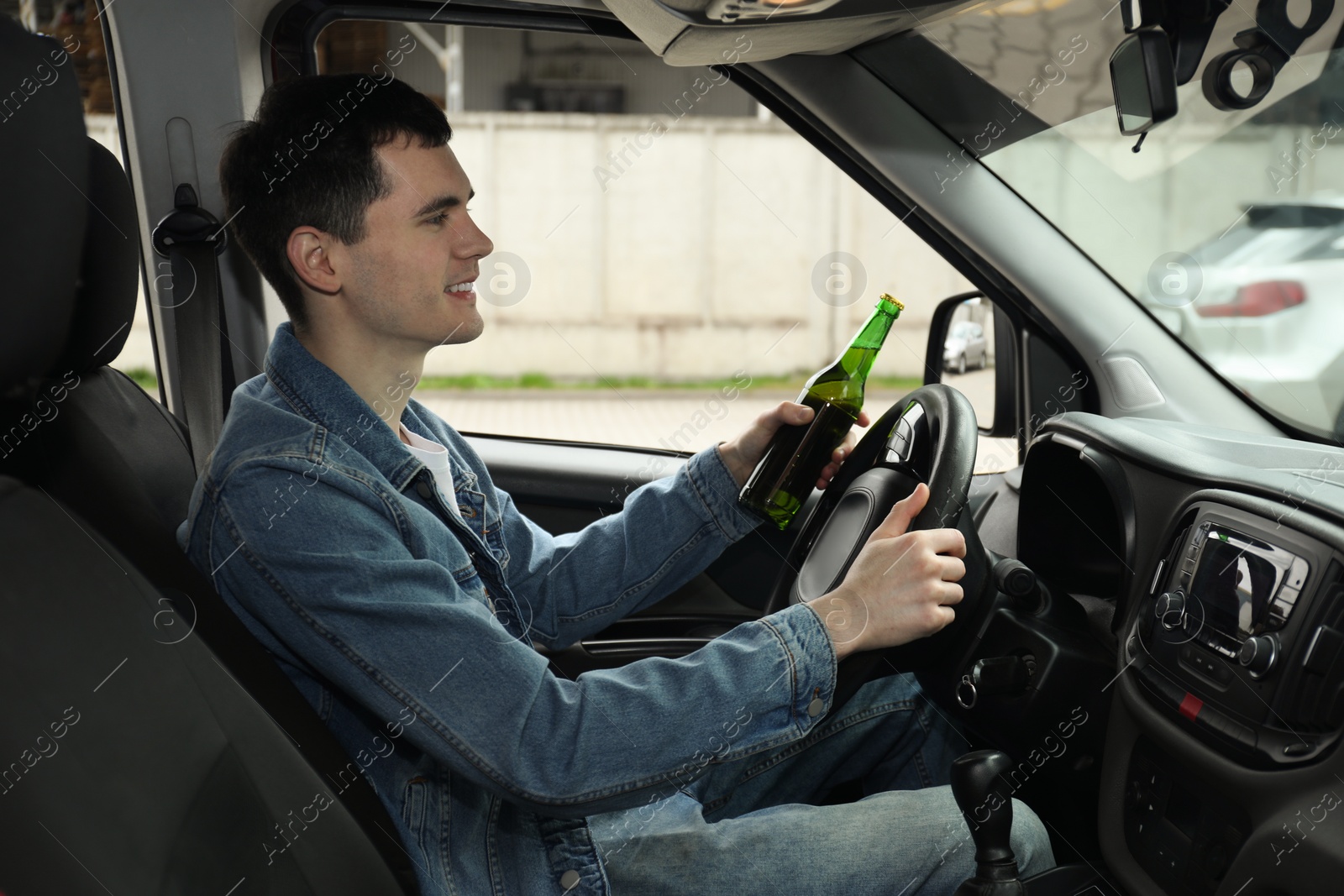 Photo of Smiling man with bottle of beer driving car. Don't drink and drive concept