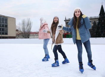 Image of Happy women skating along ice rink outdoors