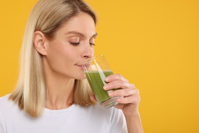 Woman drinking tasty celery juice on orange background. Space for text