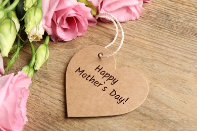 Image of Happy Mother's Day. Heart shaped greeting label and beautiful flowers on wooden table