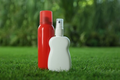 Photo of Different insect repellents on green grass. Space for text