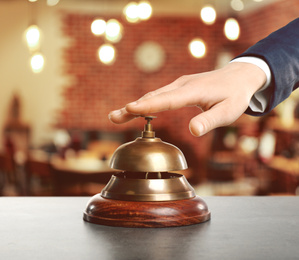 Image of Man ringing hotel service bell on blurred background, closeup