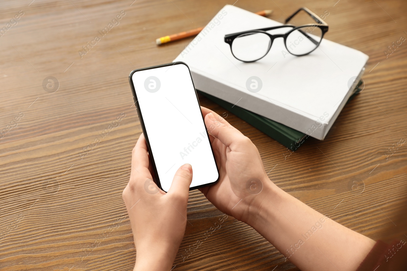 Image of Woman holding mobile phone with empty screen at wooden table, closeup